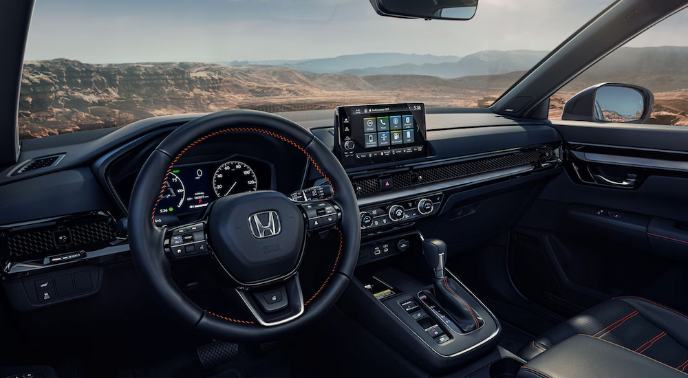 The steering wheel and infotainment screen in the cabin of a 2025 Honda CR-V Hybrid Sport Touring.