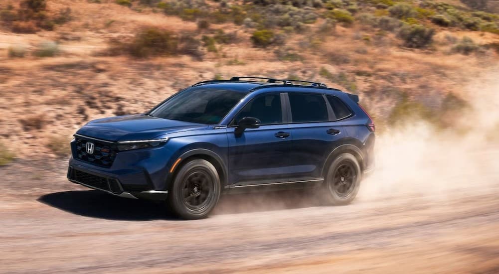A blue 2026 Honda CR-V TrailSport Hybrid off-roading.