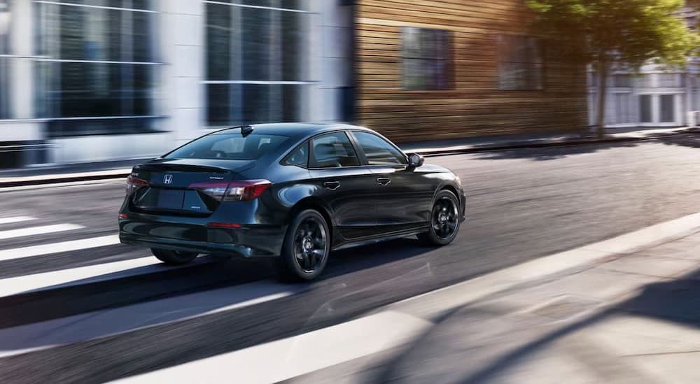 A black 2026 Honda Civic driving to a Honda dealer near Lisle.