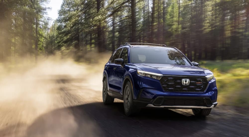 A blue 2026 Honda CR-V Hybrid off-roading on a dirt trail