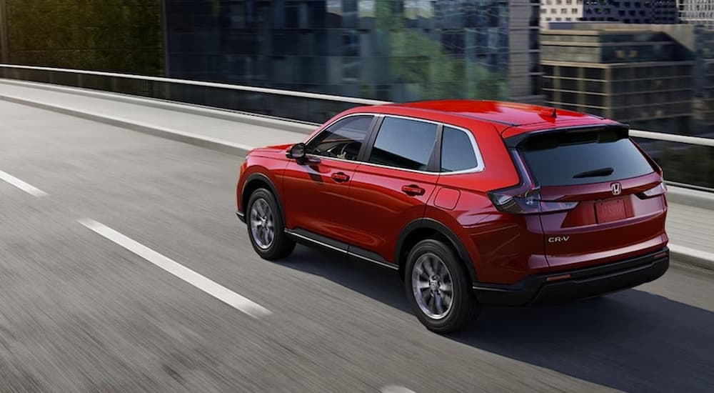 A red 2026 Honda CR-V Hybrid driving down a highway