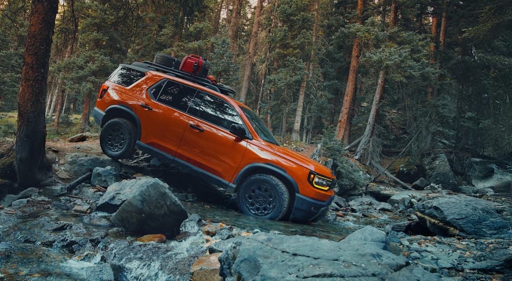 Orange 2026 Honda Passport Trailsport off-roading on a rocky trail