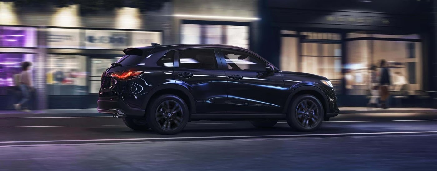 Black 2027 Honda HR-V Sport driving on a city street at night