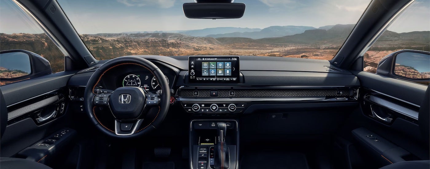 The black interior of a 2025 Honda CR-V Hybrid is shown from the driver's seat.