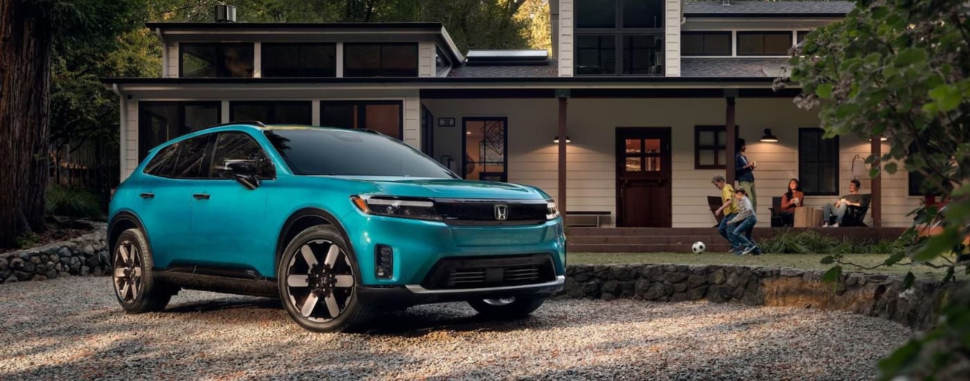 A teal 2024 Honda Prologue Elite is shown parked in front of a house.