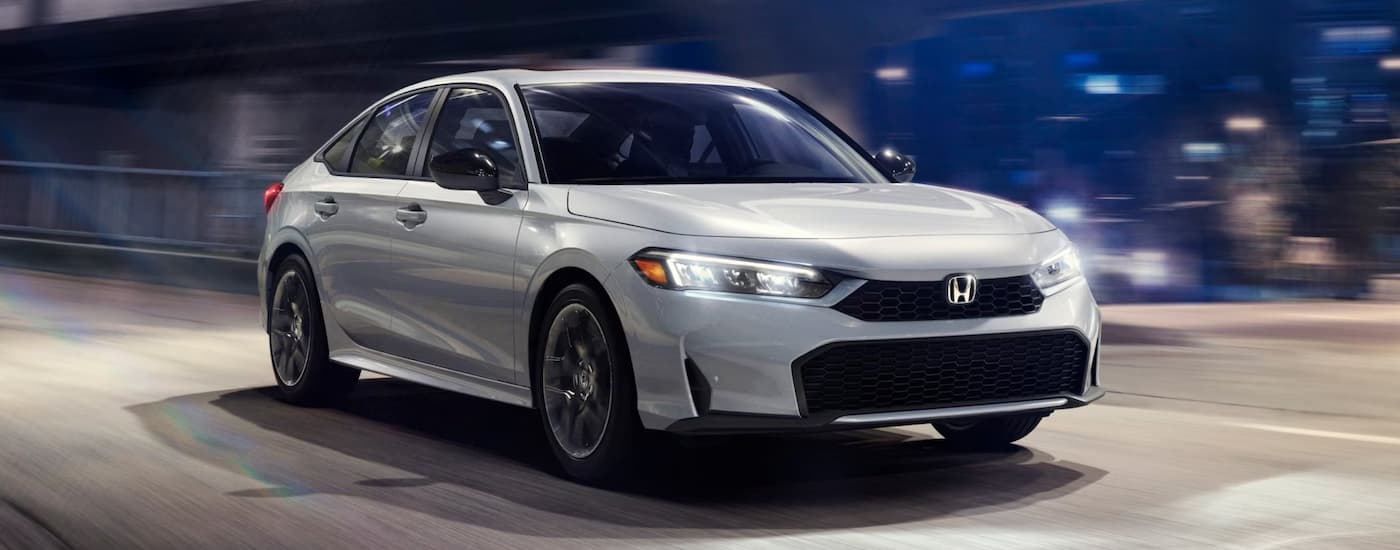 White 2025 Honda Civic driving down a road.