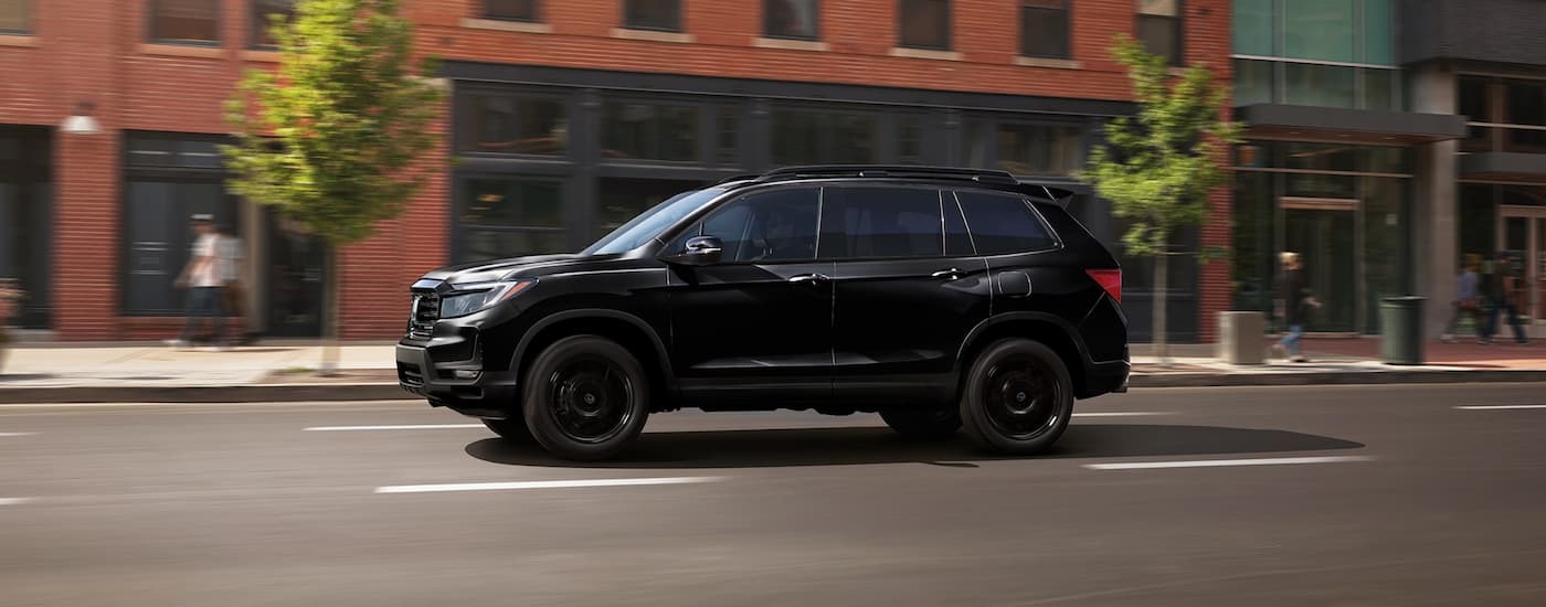 A black 2024 Honda Passport driving after leaving a Honda dealer near Elgin.