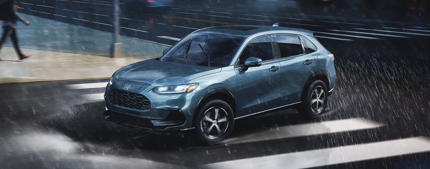 A blue 2025 Honda HR-V driving on a rainy day.