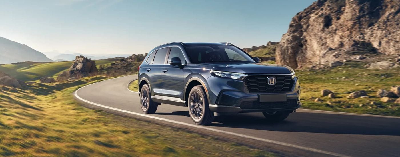 A blue 2025 Honda CR-V Hybrid driving down a highway